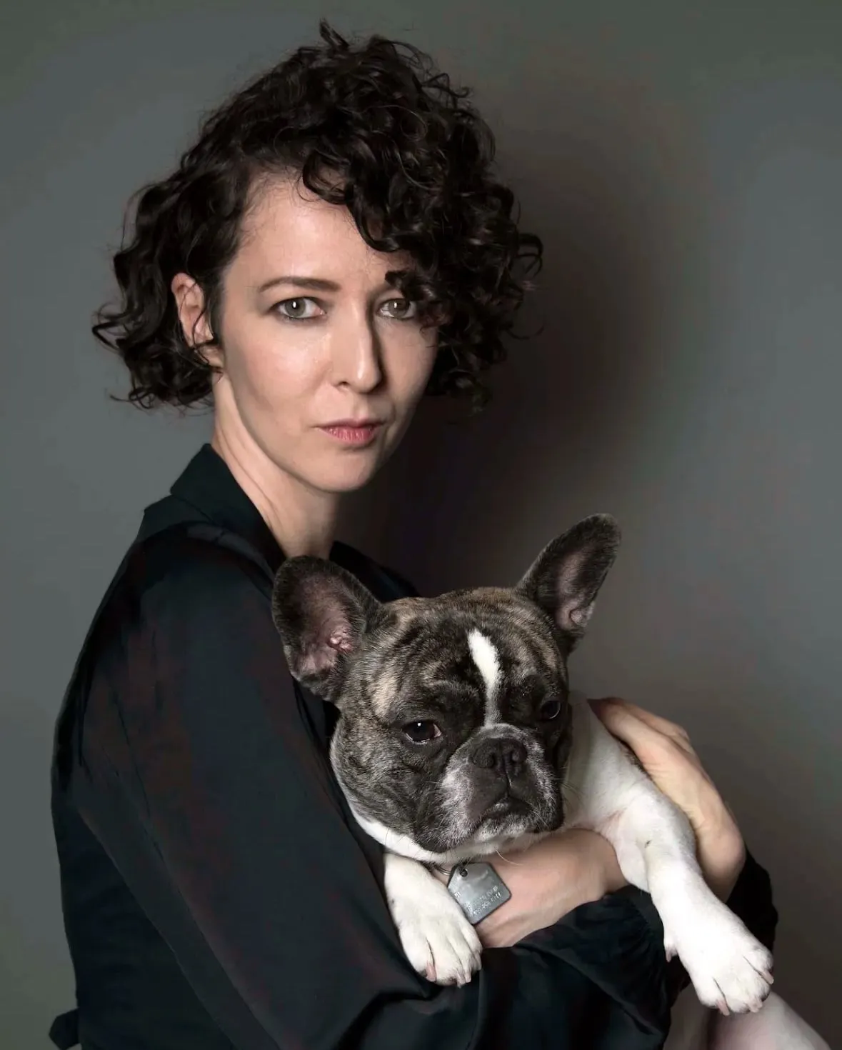 The artist, Yana Emasheva, smiling and hugging her dog.